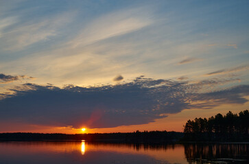 Sunrise in the cloudy sky over the water surface