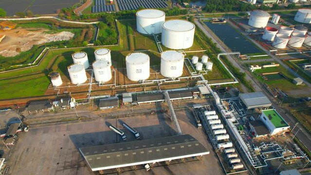 Aerial view from a drone flying over oil industrial plants and large oil storage tanks, Pipeline fuel transportation and logistics. Business power and energy industry. Fossil fuel concept. Asia
