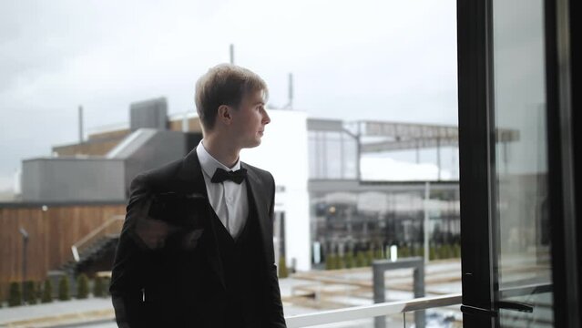 Portrait of blond man in black suit close-up. Preparing to go to bride. Wedding day. Successful businessman, groom in white shirt. Close-up shot. Slow motion footage, indoors