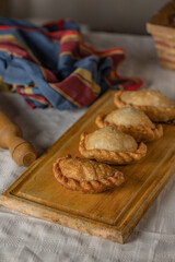 Fried Argentine empanadas on a wooden board.