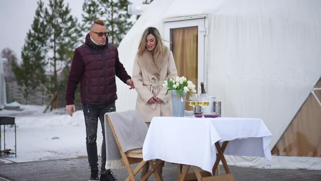 Wide Shot Confident Adult Couple Walking To Romantic Valentine's Dinner Table Outdoors On Winter Day. Positive Beautiful Caucasian Woman And Handsome Man Dining On Terrace Celebrating Holiday