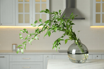 Decorative vase with branch on table in kitchen