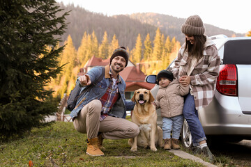 Parents, their daughter and dog near car in mountains. Family traveling with pet