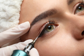 Young woman undergoing procedure of permanent eye makeup, closeup - obrazy, fototapety, plakaty