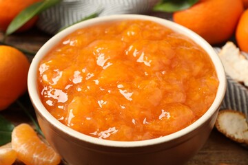 Tasty tangerine jam in bowl on wooden table, closeup