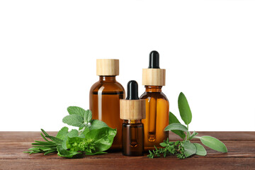 Bottles of essential oil and fresh herbs on wooden table against white background