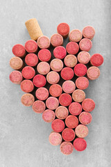 Grape made of wine bottle corks on grey table, top view
