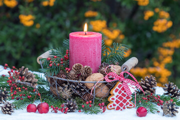 rote Kerze, Zapfen und Walnüsse im Körbchen als Weihnachtsdekoration