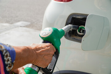 feminine hand refuel petrol in her vehicle. gasoline cost and crisis