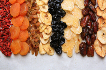 Different tasty dried fruits on paper, flat lay