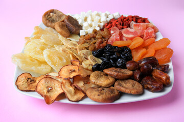 Plate with different dried fruits on violet background, closeup