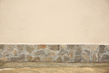 Beautiful beige wall with stone fragments and concrete floor