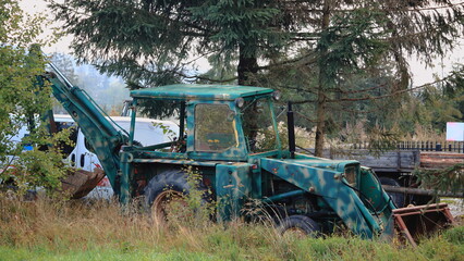 An old backhoe loader standing somewhere among the greenery. Stara koparko-ładowarka stojąca gdzieś wśród zieleni. © jarizPJ