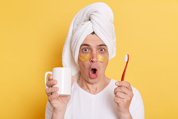 Portrait of amazed shocked surprised man wearing white T-shirt and being wrapped in towel standing...