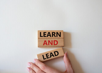 Learn and lead symbol. Concept words Learn and lead on wooden blocks. Beautiful white background. Businessman hand. Business and Learn and lead concept. Copy space.