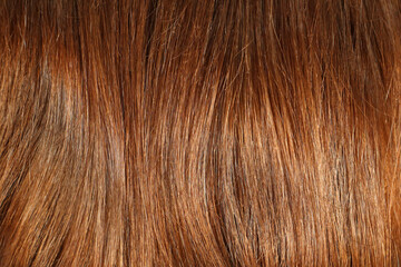 Hair texture close up chestnut golden brown color, closeup view of bunch of shiny straight brown hair in wavy curved style.