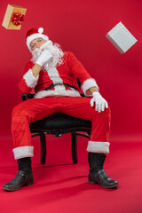 Portrait von einem verkleideten Weihnachtsmann mit Geschenk, isoliert auf roten Hintergrund im Studio mit Platzhalter