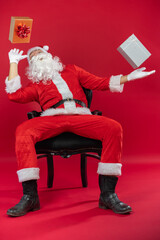 Portrait von einem verkleideten Weihnachtsmann mit Geschenk, isoliert auf roten Hintergrund im...