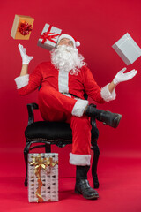 Portrait von einem verkleideten Weihnachtsmann mit Geschenk, isoliert auf roten Hintergrund im Studio 