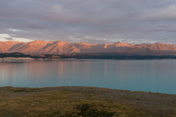 Lake Pukaki mit türkisem Wasser und glühenden Bergen zum Sonnenaufgang.