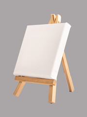 Empty blank white canvas mock up on mini wooden tripod easel on gray background