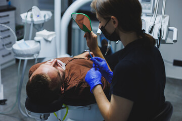 Orthodontic treatment of teeth. The doctor installs metal braces on the patient's teeth. Oral care....