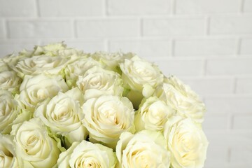 Luxury bouquet of fresh roses near white brick wall, closeup