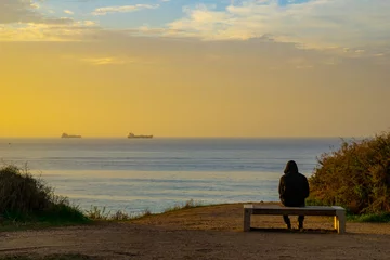 Zelfklevend Fotobehang silhouette of a person sitting on a bench at sunset © reznik_val