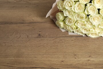 Luxury bouquet of fresh roses on wooden table, space for text