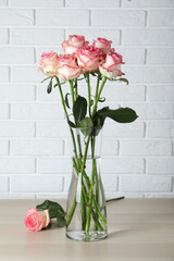 Vase with beautiful pink roses on wooden table