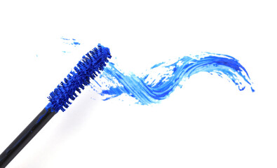 Applicator and blue mascara smear on white background, top view