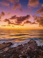 Obraz premium Surfs up sunrise at the seaside with scattered clouds