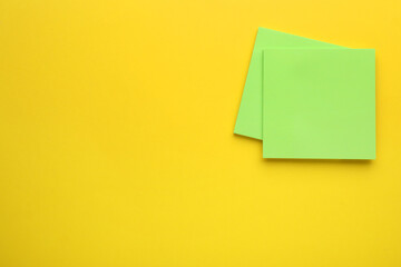 Paper notes on yellow background, top view. Space for text
