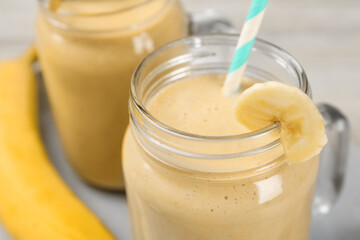 Tasty banana smoothie with straw on table, closeup view
