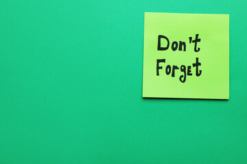 Paper note with phrase Don't Forget on green background, top view. Space for text
