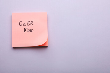 Paper note with phrase Call mom on light grey background, top view. Space for text