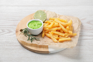 Delicious french fries, avocado dip, lime and rosemary served on white wooden table