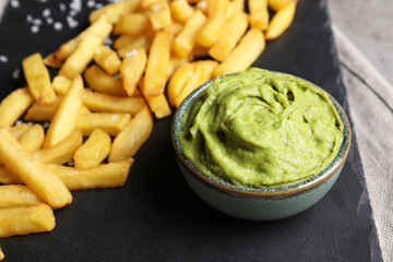 French fries and avocado dip on serving board, closeup