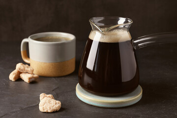 Turkish coffee in glass cezve and cup on dark grey table