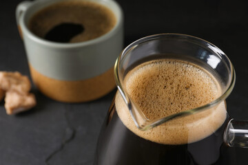 Turkish coffee in cezve and cup on dark grey table, closeup