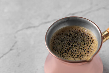Turkish coffee in cezve on light grey table, closeup. Space for text