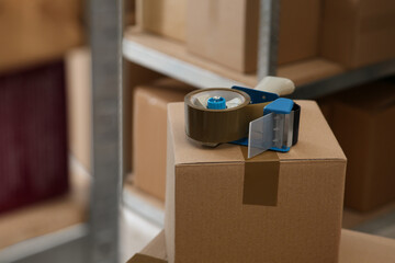 Adhesive tape dispenser on cardboard box indoors. Space for text