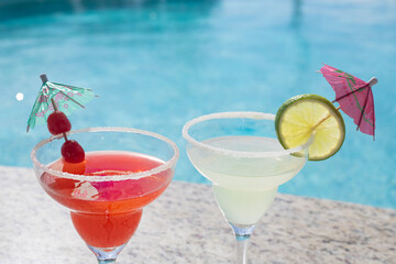 MARGARITAS. CHERRY AND LEMON DAISIES ON THE EDGE OF A POOL ON A SUNNY DAY