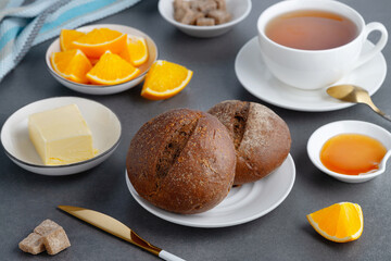 Rye buns and breakfast butter with tea and orange