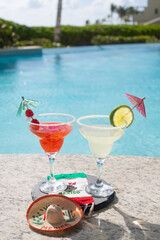 CHERRY AND LEMON DAISIES ON THE EDGE OF A POOL ON A SUNNY DAY WITH A MEXICAN FLAG TABLECLOTH WITH...