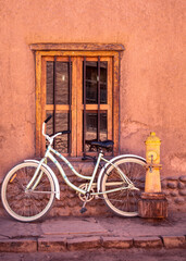 Fototapeta na wymiar White bicycle, window and yellow fure hydrant on a street San Pedro Atacama, Chile