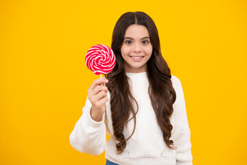 Teenager girl eating sugar lollypop. Candy and sweets for kids. Child eat lollipop popsicle over yellow isolated background. Yummy caramel, candy shop. Happy smiling girl.