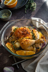Oven roasted coquelet jaune (yellow spring chicken) with oranges, onions and herb butter in glass baking dish.