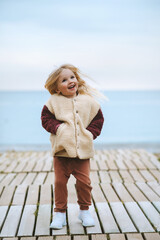 Child walking on the beach outdoor girl wearing fluffy sherpa jacket fashion outfit winter stylish...