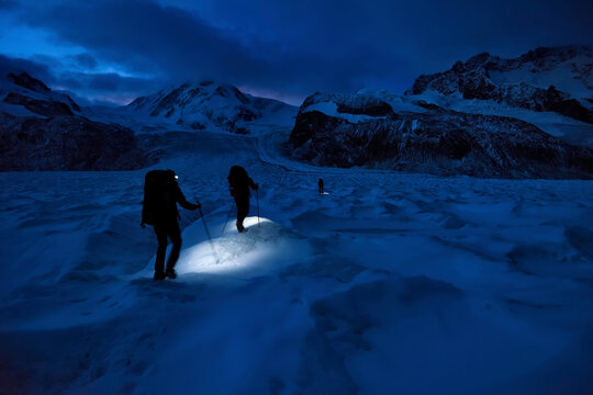 Cave explorers hiking over the glacier in search of new, unexplored moulins on Gorner Glacier.; Gornergrat, Zermatt, Switzerland.